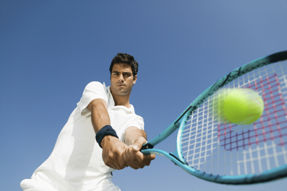 A low angle view of a tennis player hitting a shot with the racket