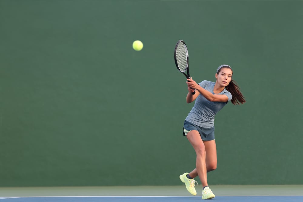 A view of a girl hitting tennis backhand technique shot