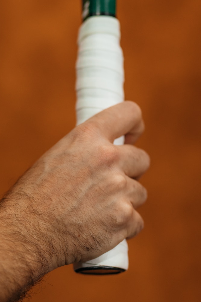 A view of a person gripping a tennis racket with forehand grip