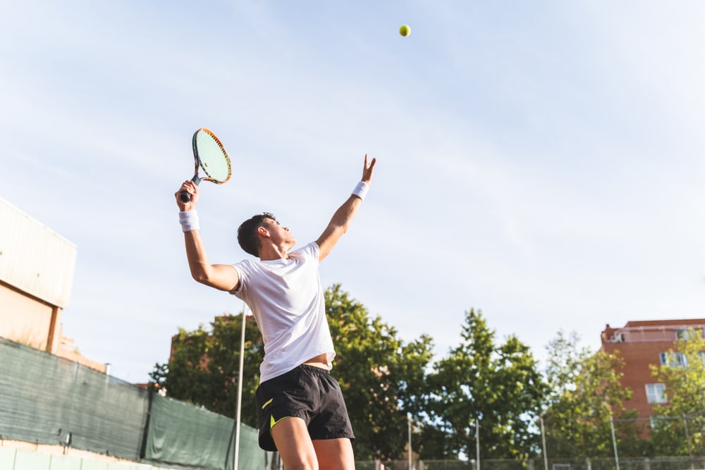 A view of a person hitting a tennis ball high up in the air