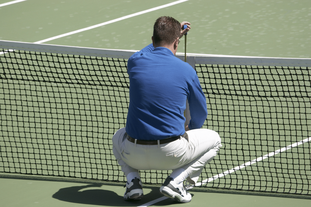 A view of a person measuring the tennis net height