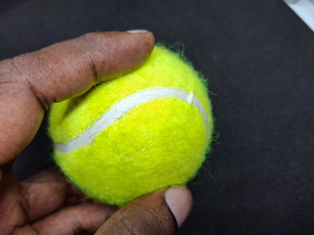 A view of a person pressing a tennis ball