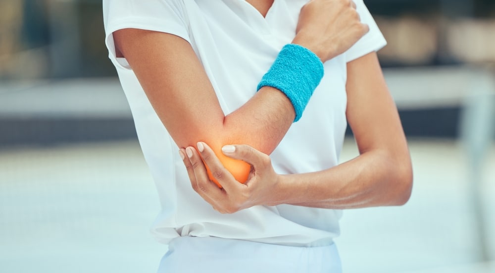 A view of a sports woman holding her elbow with tennis elbow pain