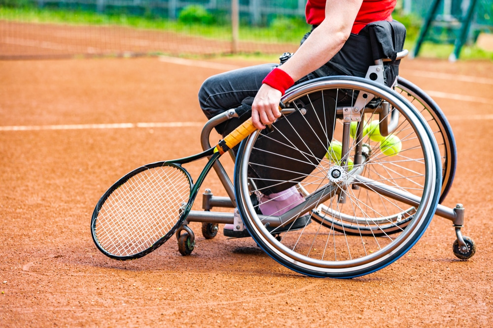 Disabled Young Woman On Wheelchair Playing Tennis On Tennis Court