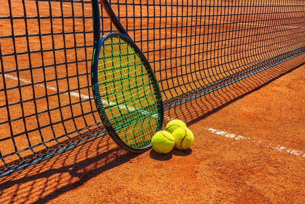 A Yellow Tennis Ball And Tennis Racket Lies On Tennis