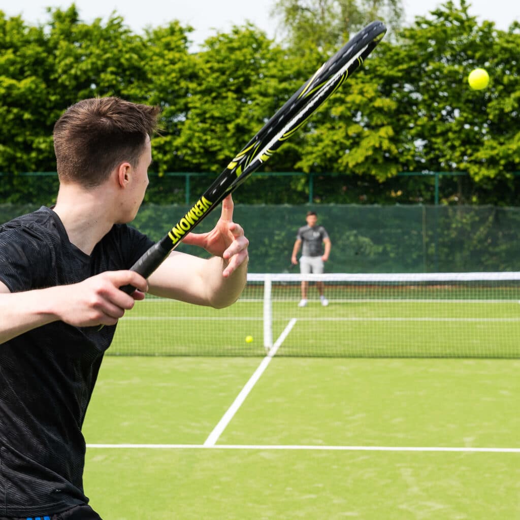 A view of a guy holding a racket playing a game of tennis with an ooponent inside a court