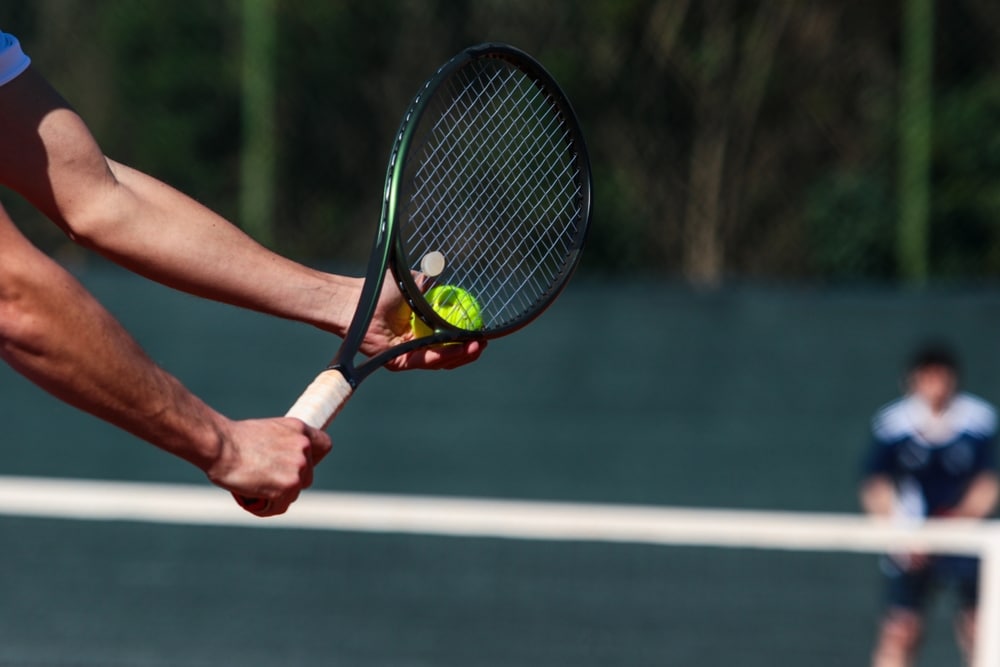 A view of a person holding the racket and a tennis ball