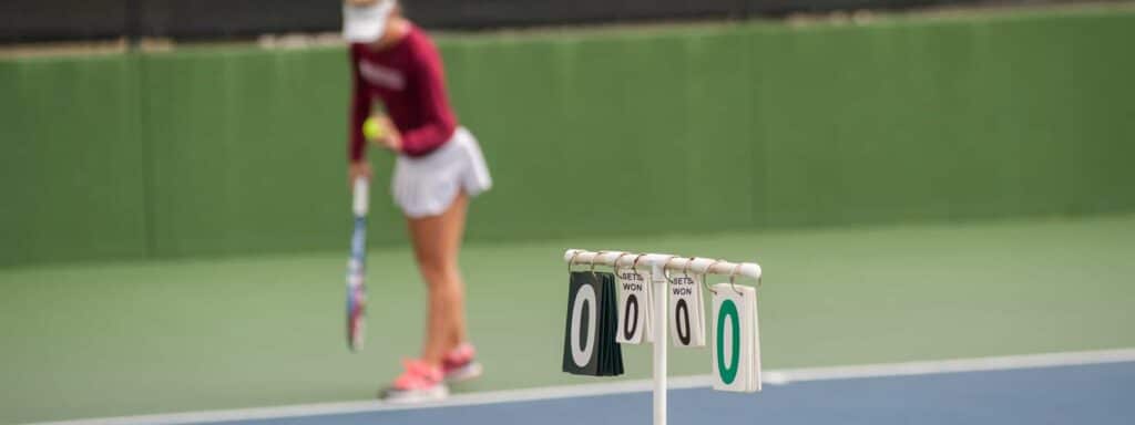 A view of a tennis point break score hanging with a blurred image of a woman serving