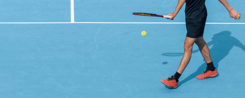 Young Tennis Player Playing With Ball And Racket On Blue