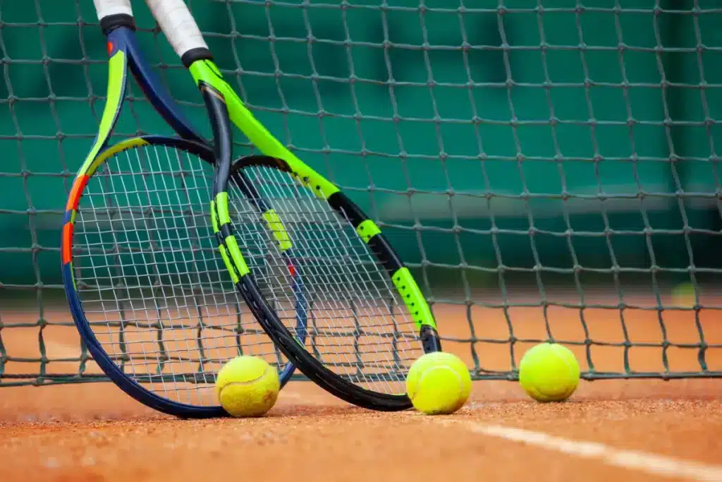 rackets and balls placed alongside a net