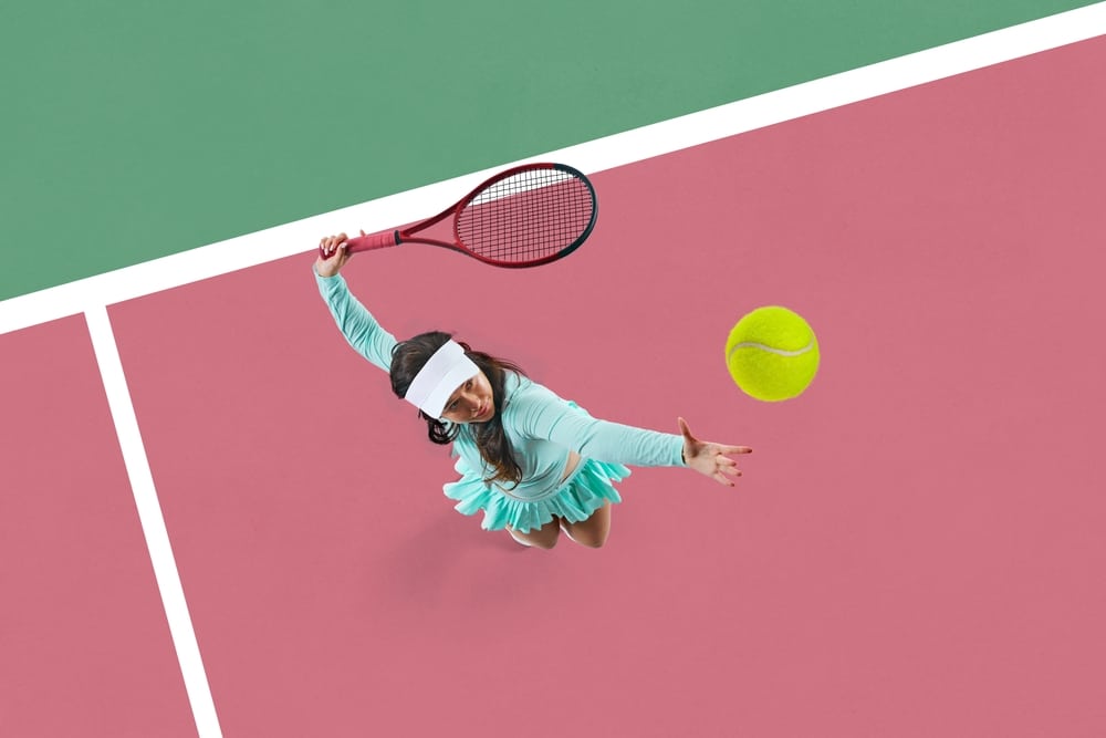 Focused young woman, tennis player in motion on court, serving ball with racket