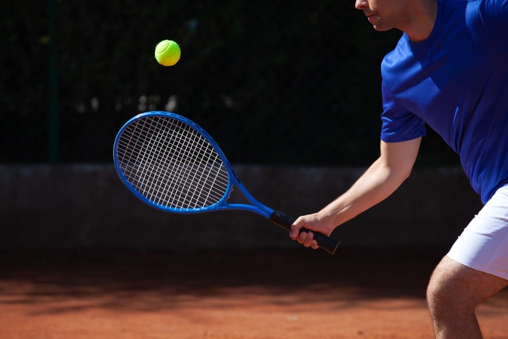 Profesional tennis player meets a ball hit by the opponent on a clay playfield 