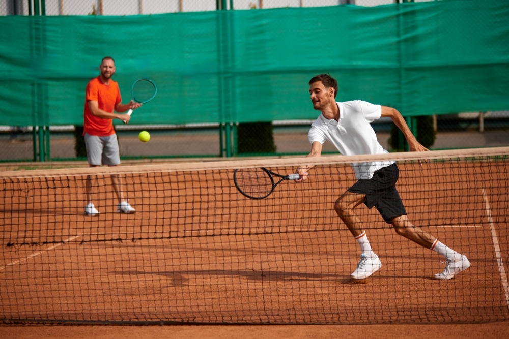 Two concentrated and ambitious tennis players in motion outdoor clay court