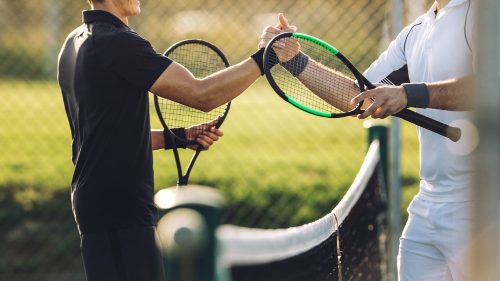 Two young man shaking hands after playing tennis showing sportsmanship