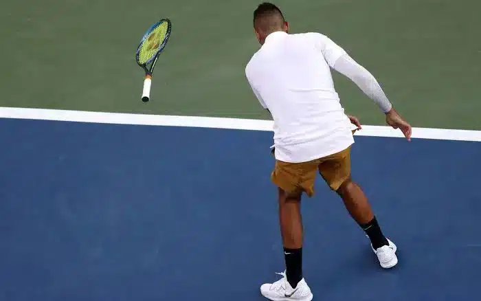 a male players back shown on the court racket in air