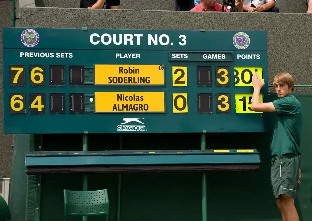 a person standing near a tennis score board