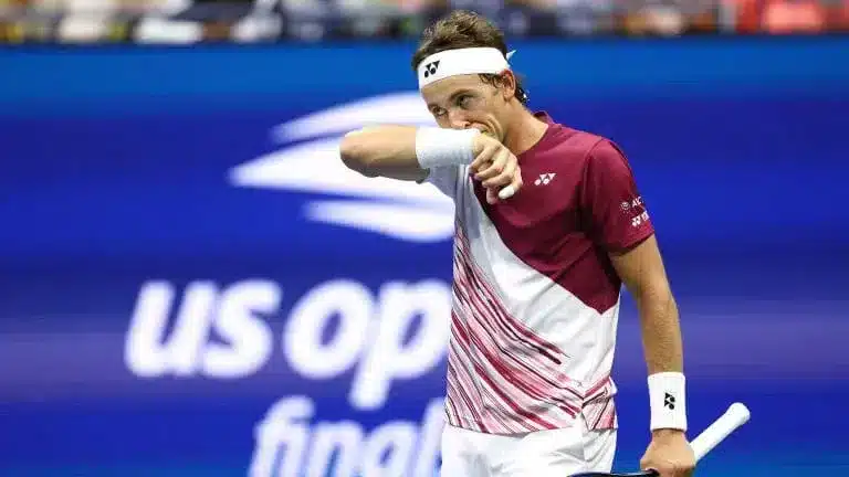 a player wiping off the sweat with one arm holding racket in other