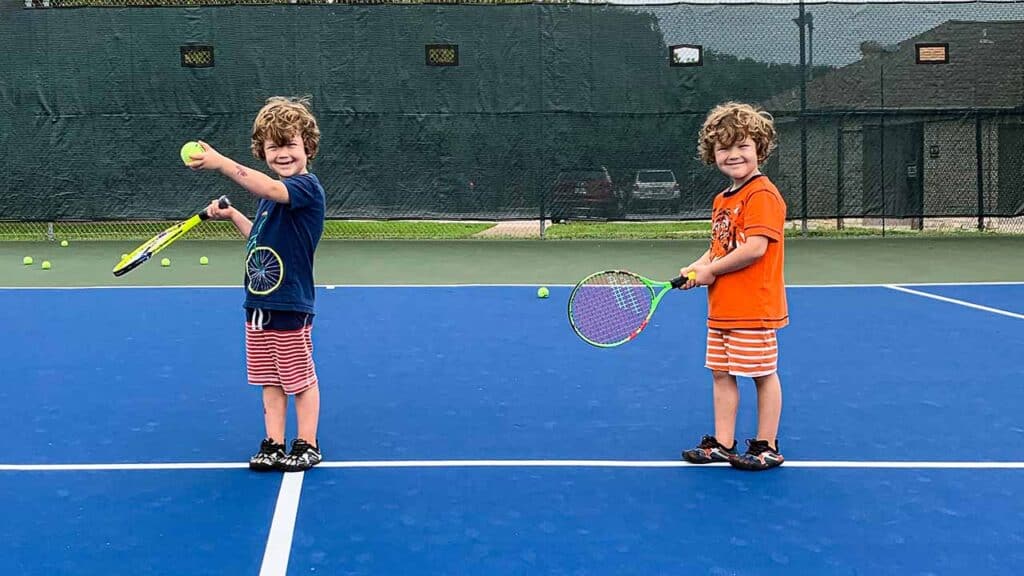 kids holding rackets standing on a court