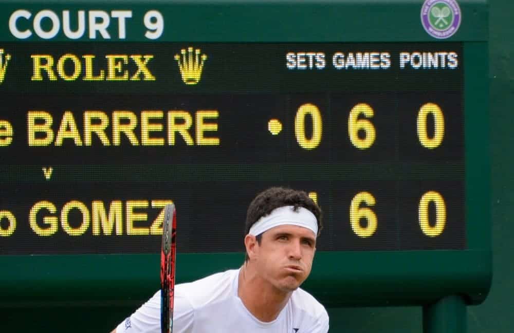 zoomed in view of a tennis player with anxious face scoreboard in the background