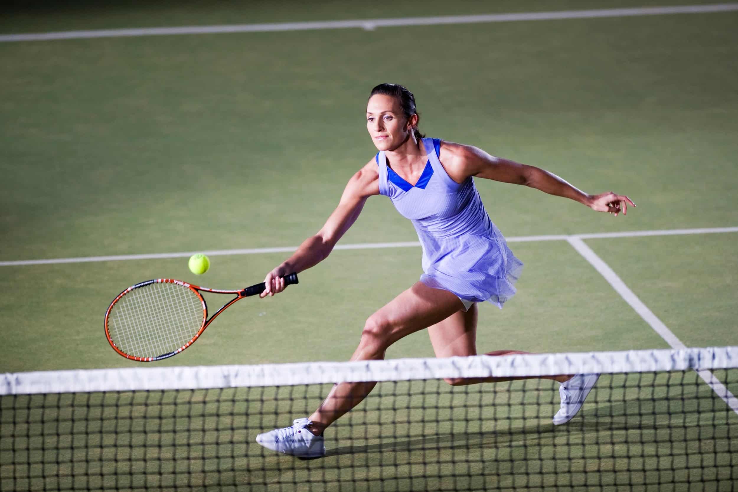 a female tennis player holding racket hitting a shot