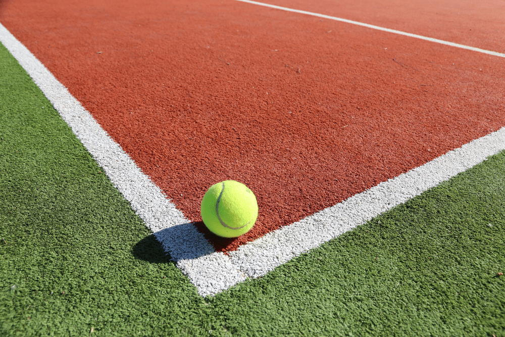 Tennis Court outdoors with tennis ball in corner of sidelines