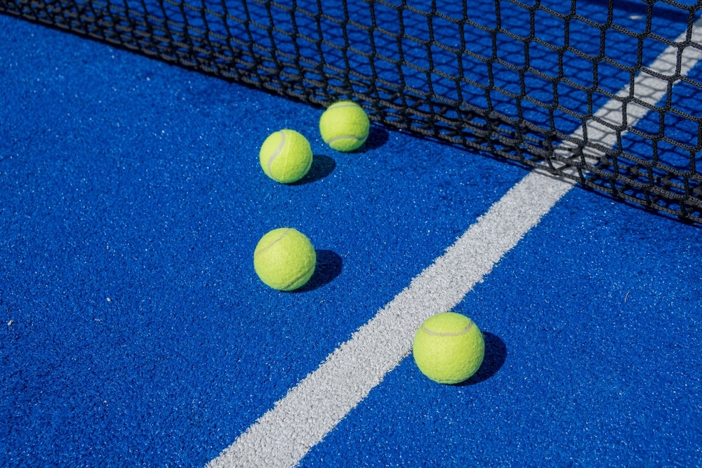 selective focus, four paddle tennis balls on a blue paddle tennis court close to the net, 